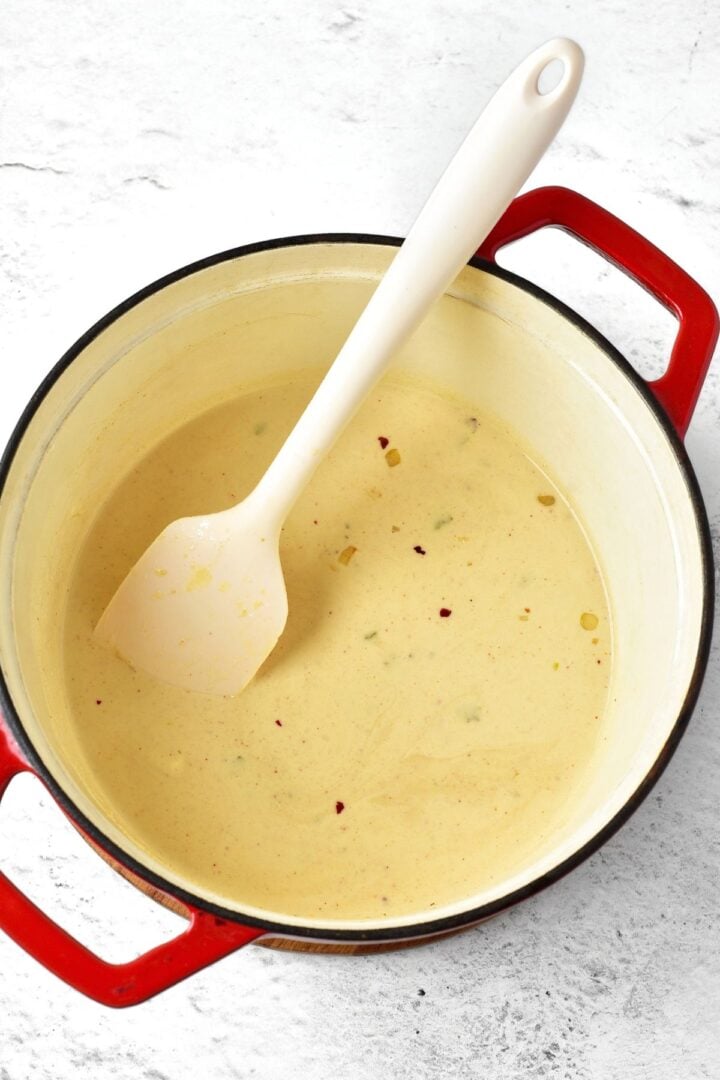 White spatula in a pot with creamy broth.
