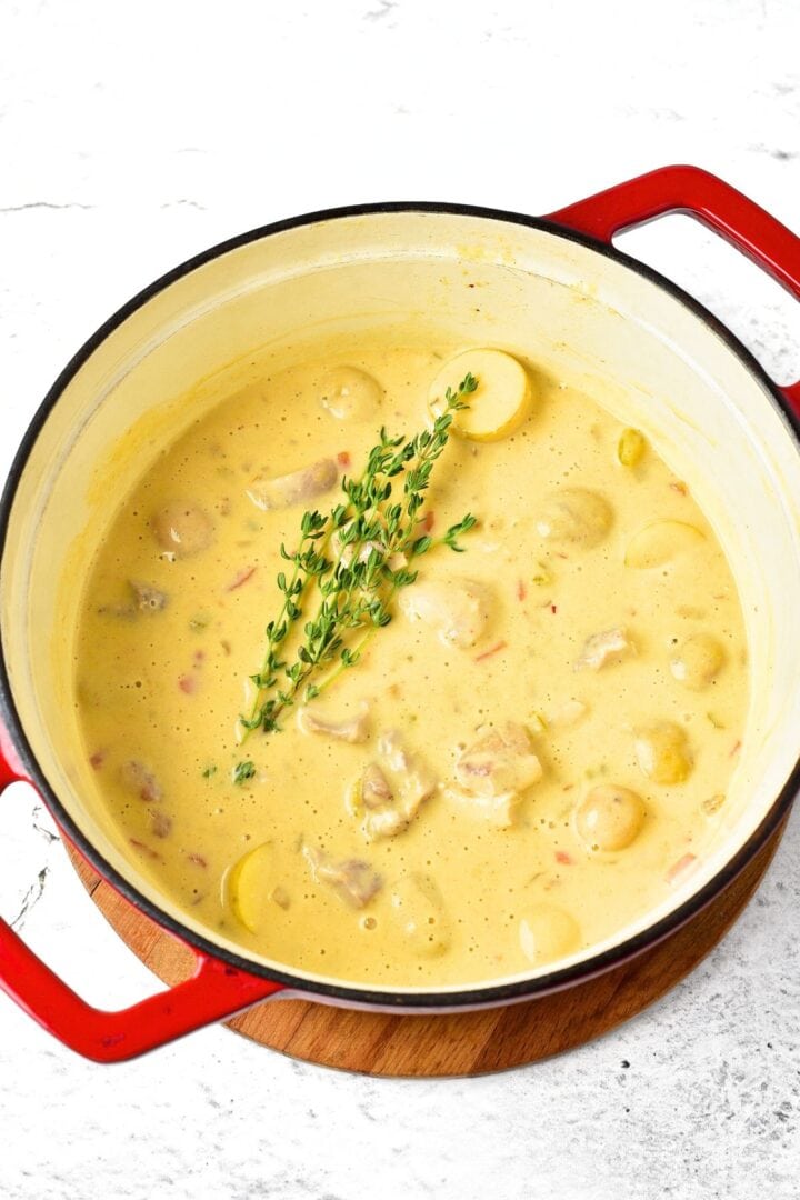 Fresh thyme sprigs in a pot of creamy soup.