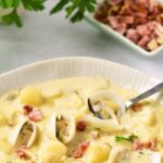 A spoon in a bowl of New England clam chowder.
