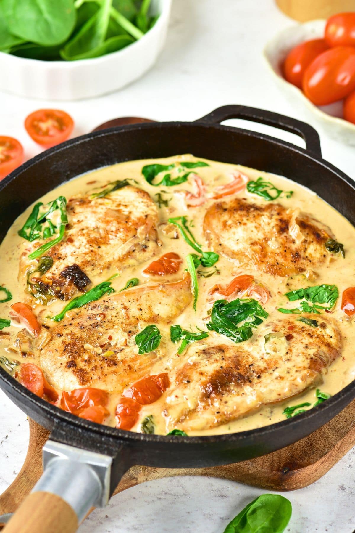 Creamy Tuscan Chicken (Gluten-Free, Dairy-Free) Creamy Tuscan chicken in cast iron skillet on wooden board.