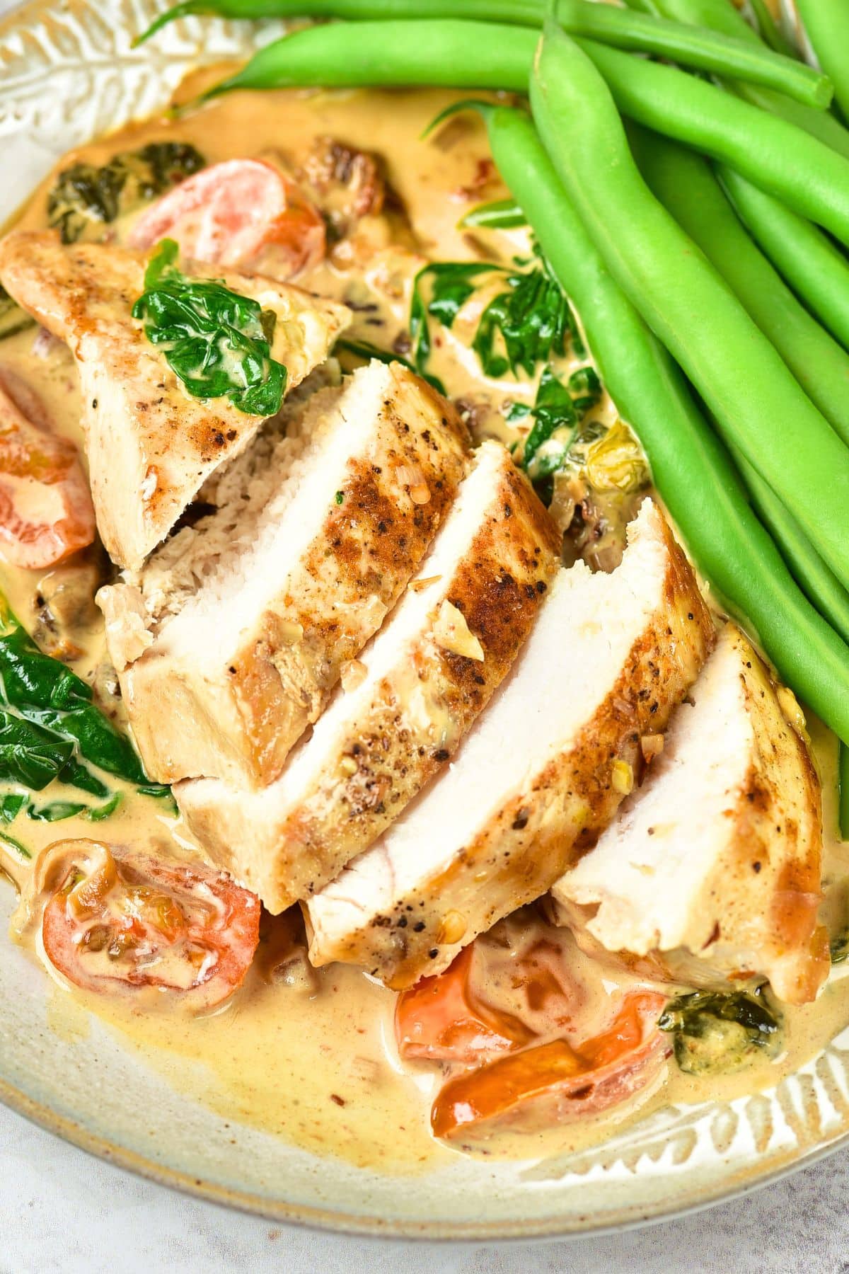 Tuscan Chicken with Sun Dried Tomatoes Sliced chicken breast on top of a creamy Tuscan chicken sauce with green beans