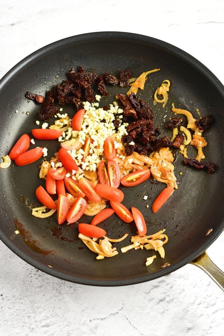 Cooking cherry tomatoes, garlic, shallots and sun-dried tomatoes in skillet