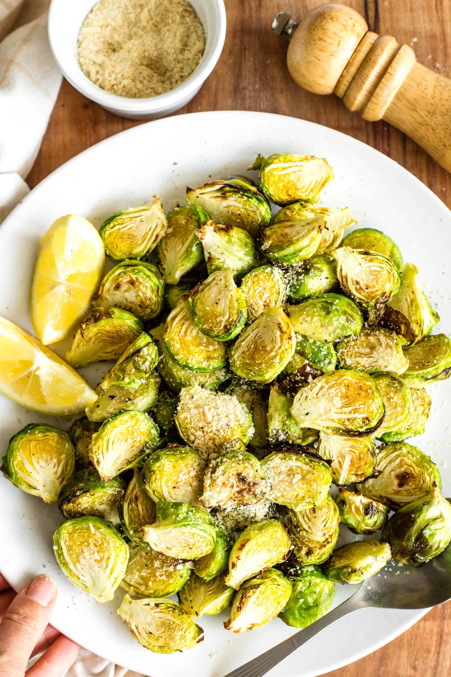 A hand holding a plate of crispy air fryer Brussels sprouts.