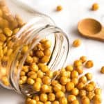 Chickpeas spilling out from a glass jar.