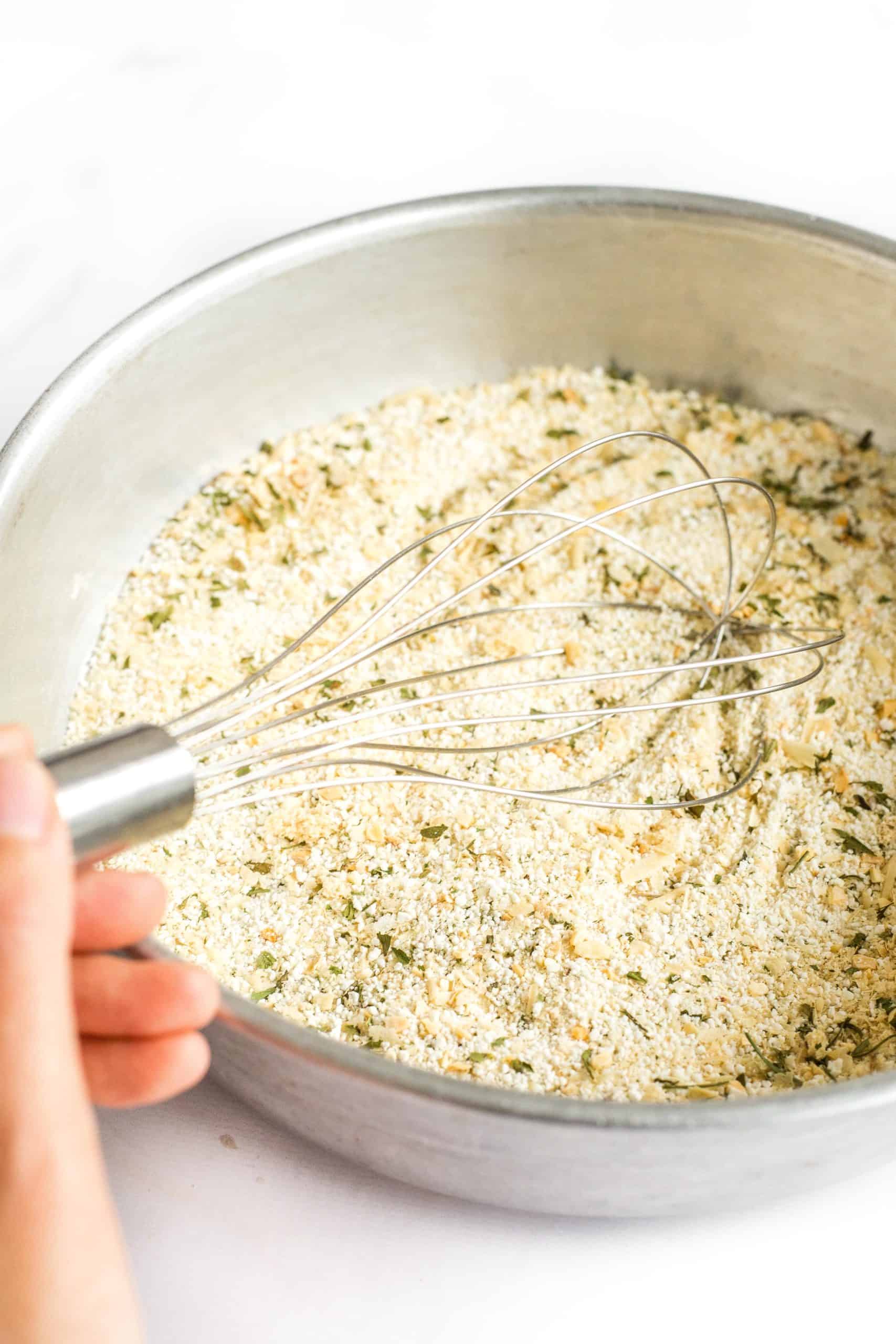 Hand whisking the ingredients for the breadcrumb mixture to make air fryer zucchini fries.