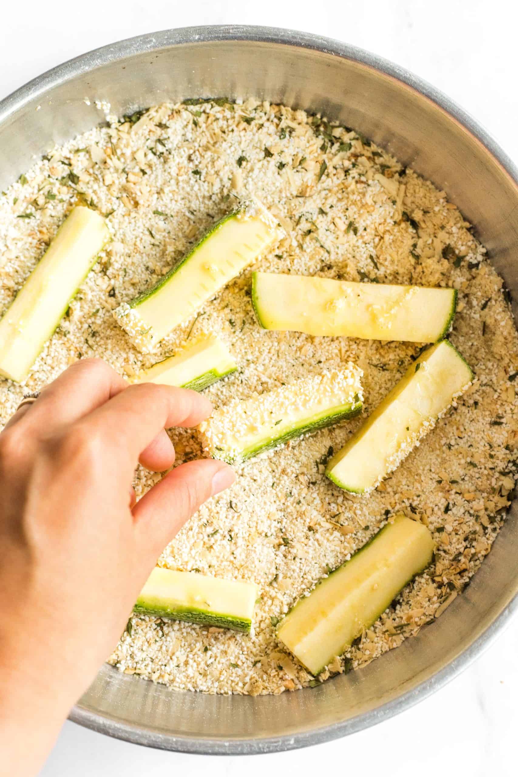 Coating zucchini sticks with a breadcrumb mixture.