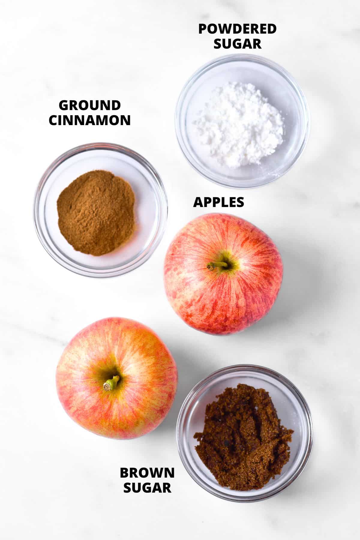 Ingredients for homemade apple chips recipe laid out on marble board.