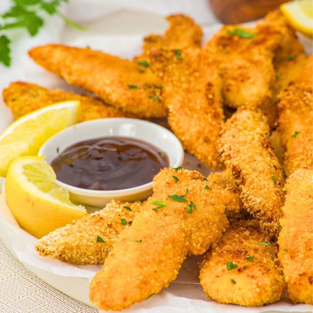 A plate of baked chicken tenders and bbq sauce.
