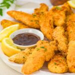 A plate of baked chicken tenders and bbq sauce.