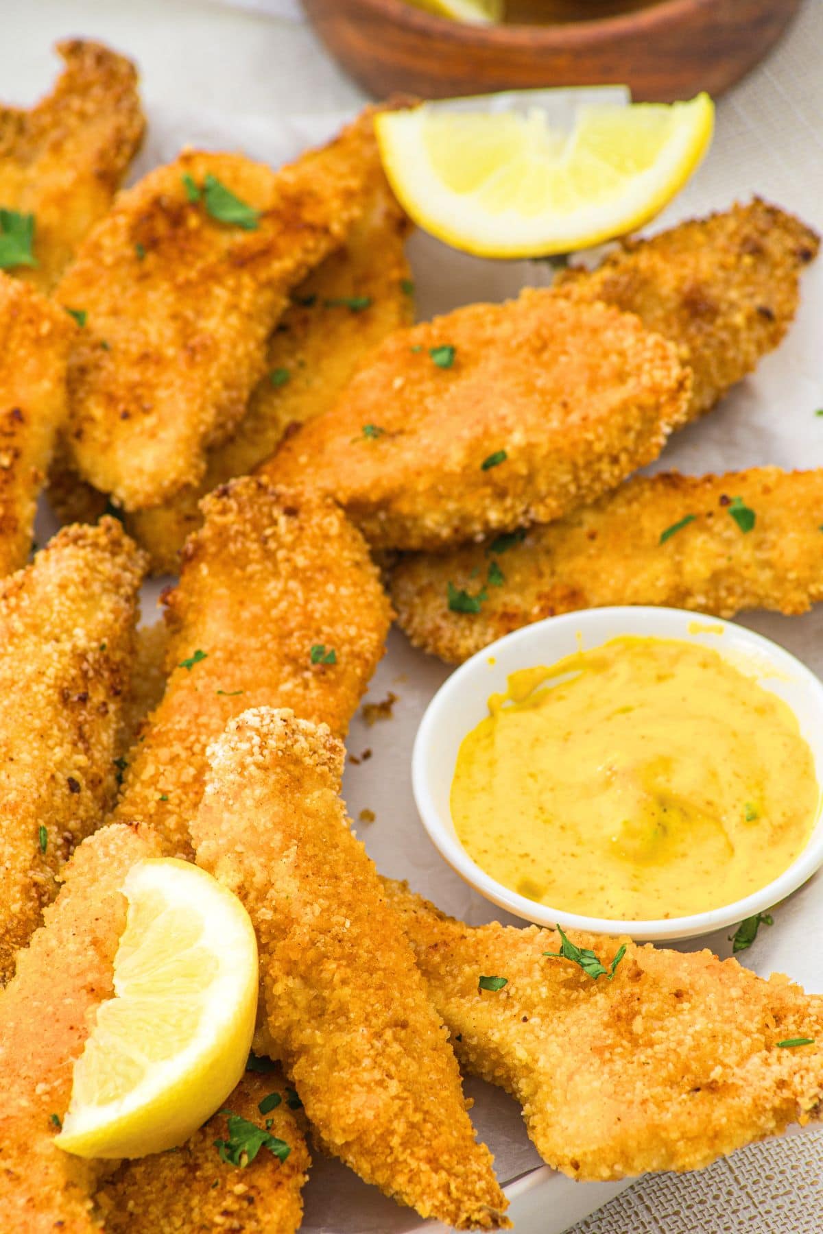 Crispy baked chicken tenders and mustard on parchment paper