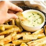 Hand dipping a baked yuca fry into cilantro lime crema.
