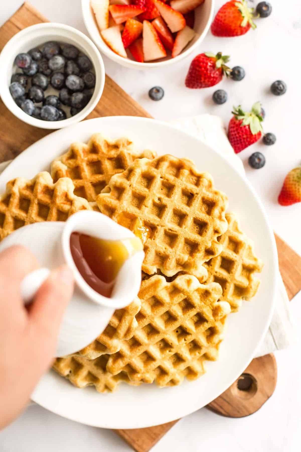 Pouring maple syrup over waffles
