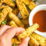 Dipping zucchini fry into a bowl of marinara sauce