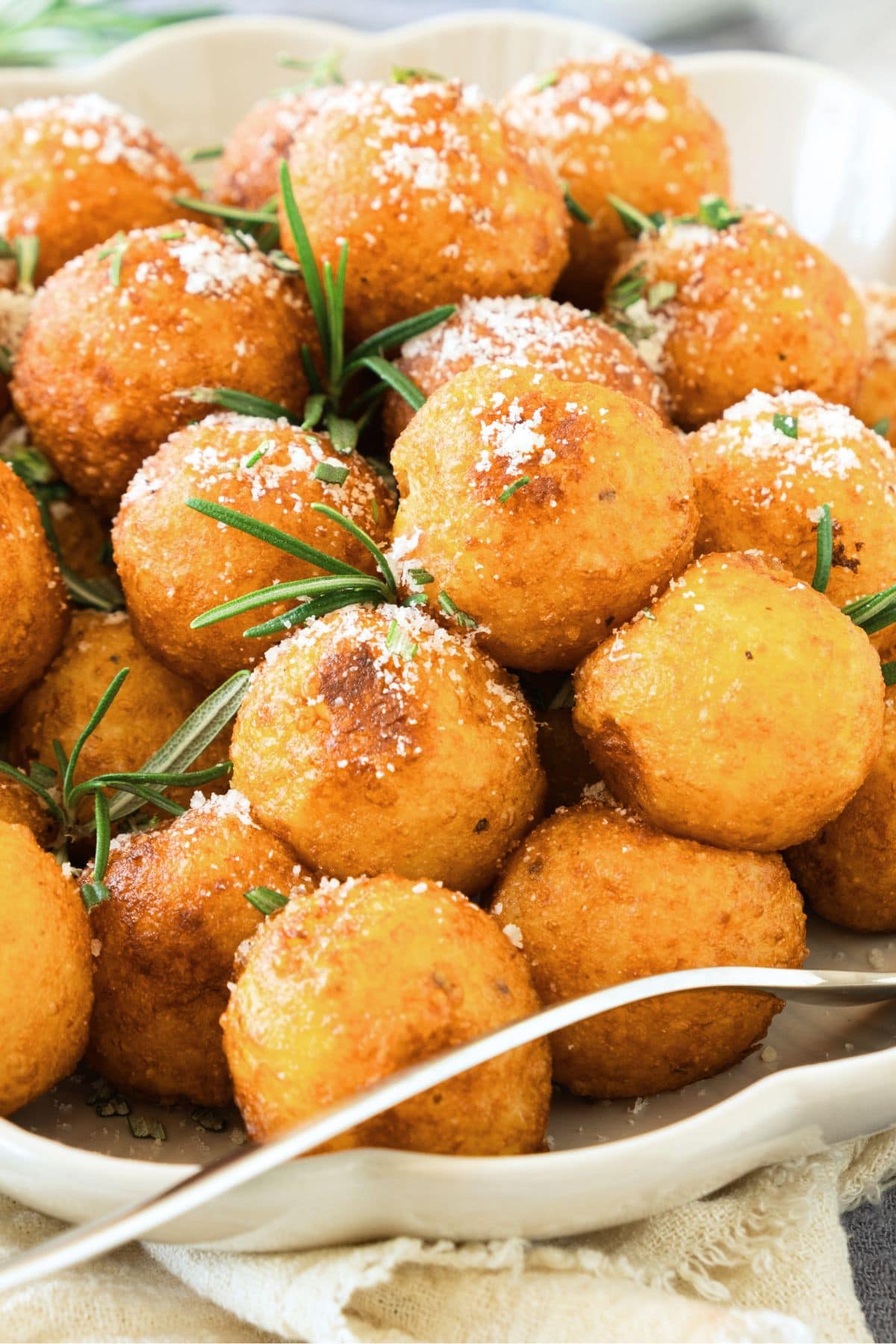 A plate of crispy potato balls sprinkled with grated parmesan cheese.