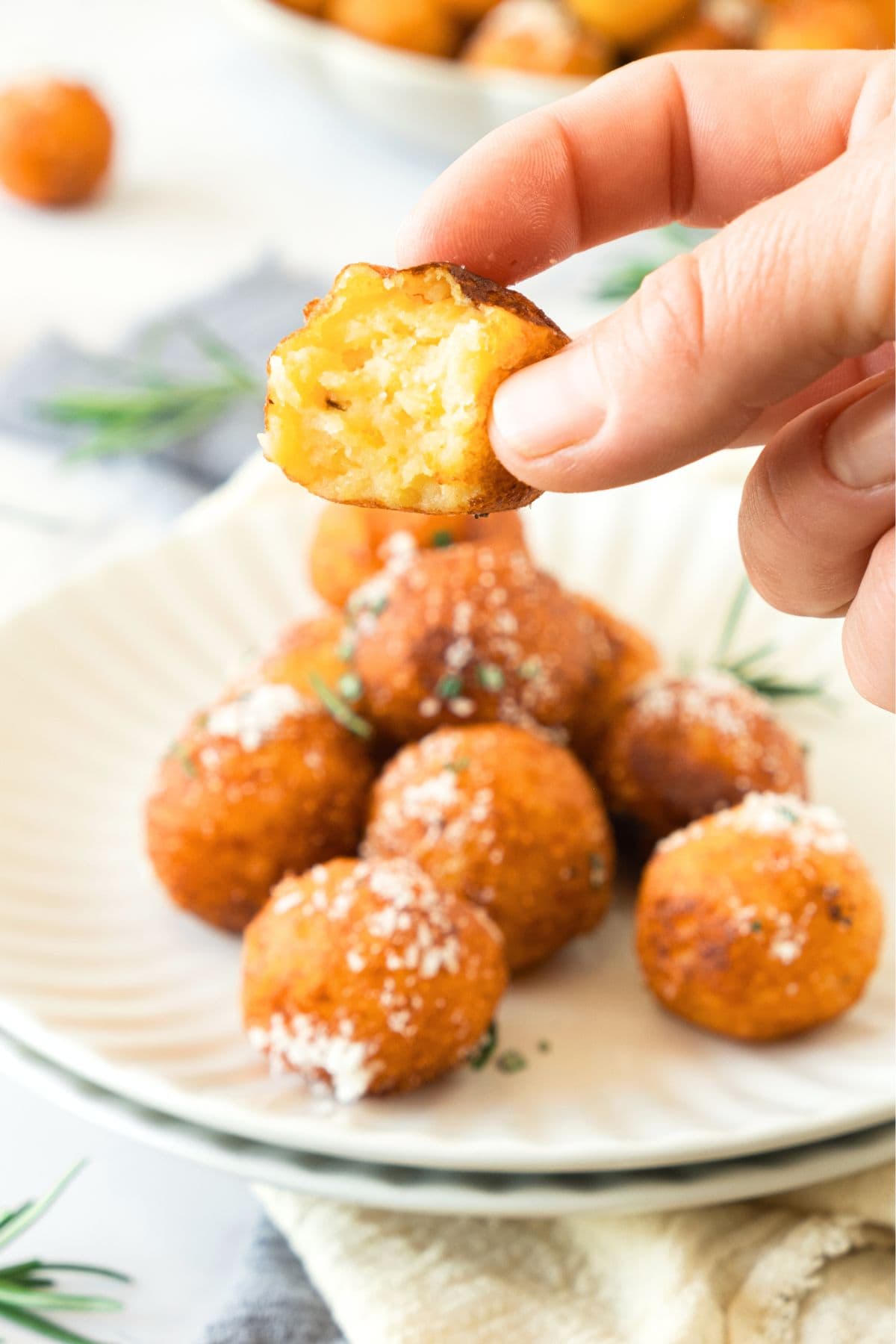 Holding up half-eaten mashed potato ball from plate.