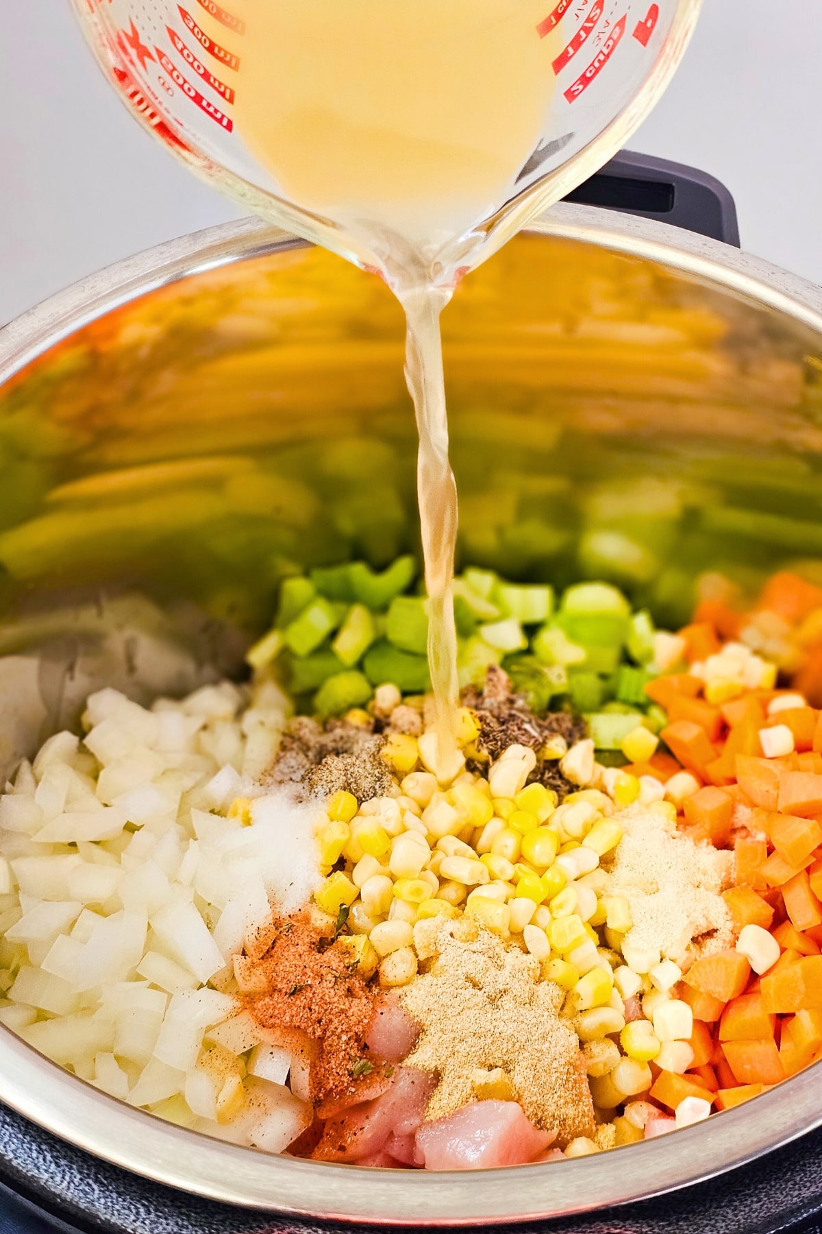 Pouring broth into ingredients in pressure cooker.