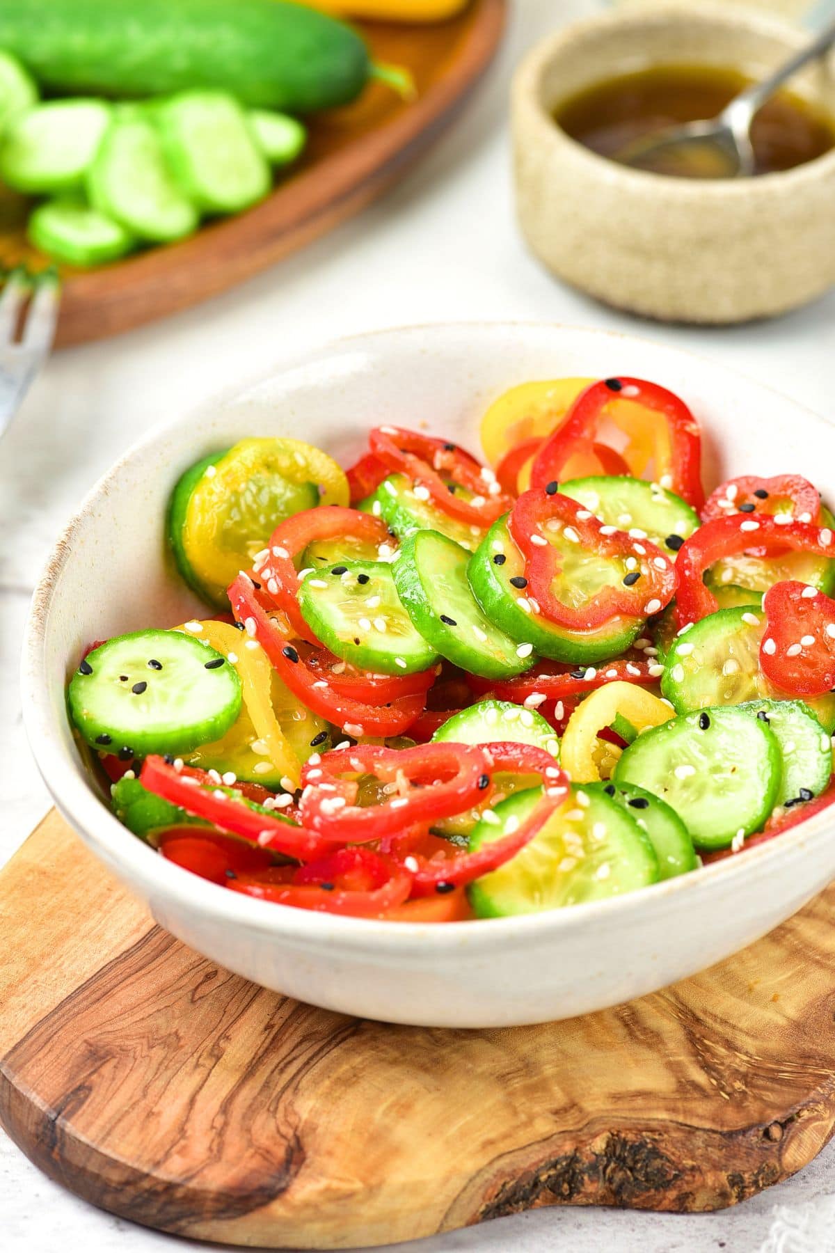 Bowl of cucumber and bell pepper salad on wooden board