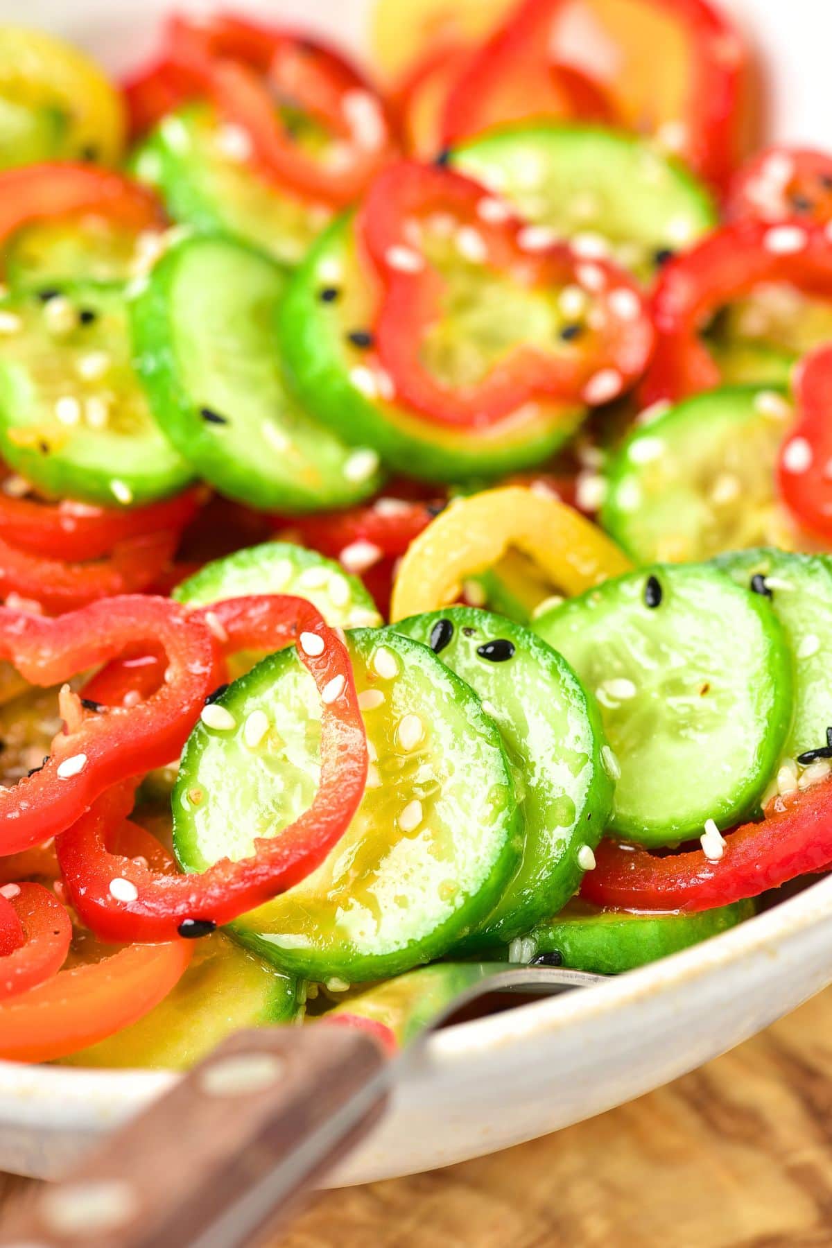 Up close view of sliced mini cucumbers and sliced mini bell peppers in bowl