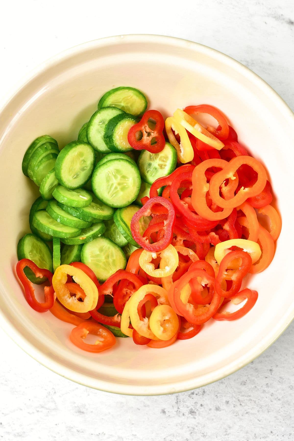 A bowl with sliced mini cucumbers and mini bell peppers