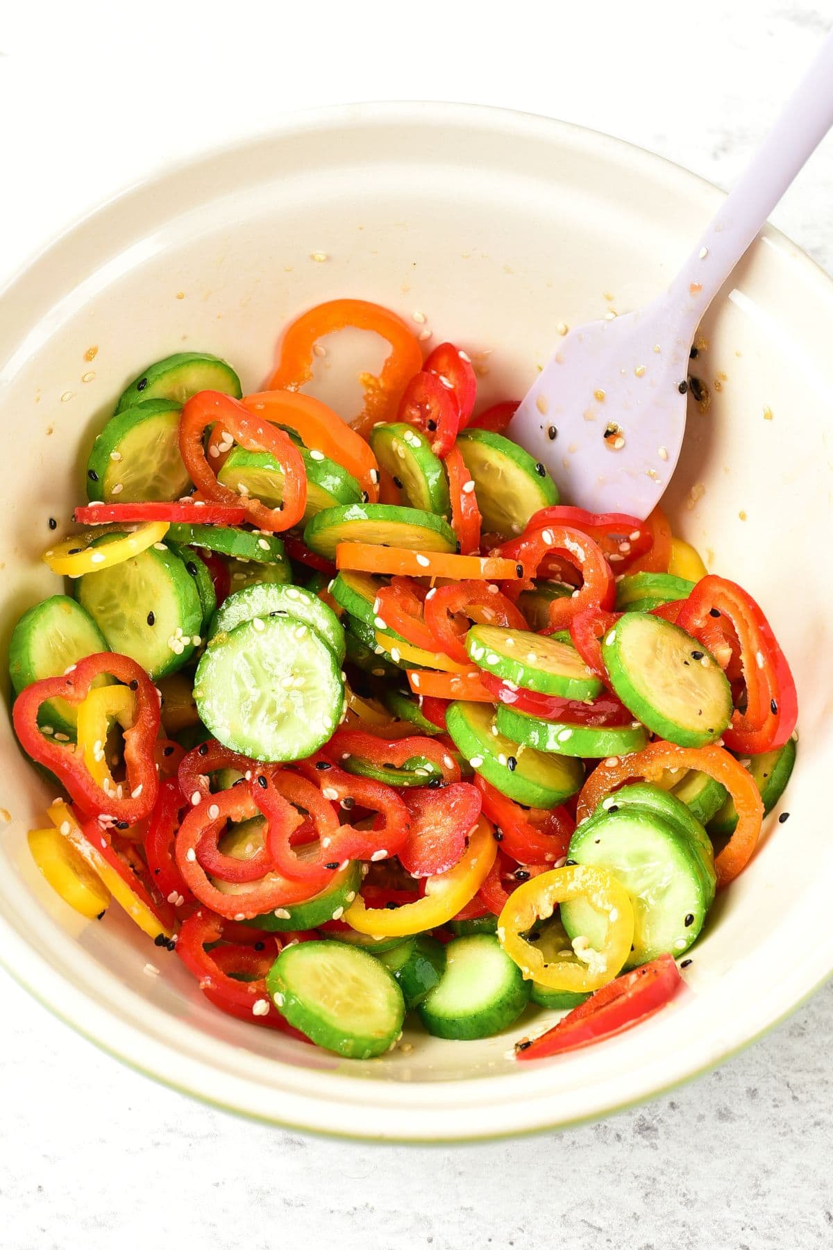 Mixing cucumbers and bell peppers in a bowl