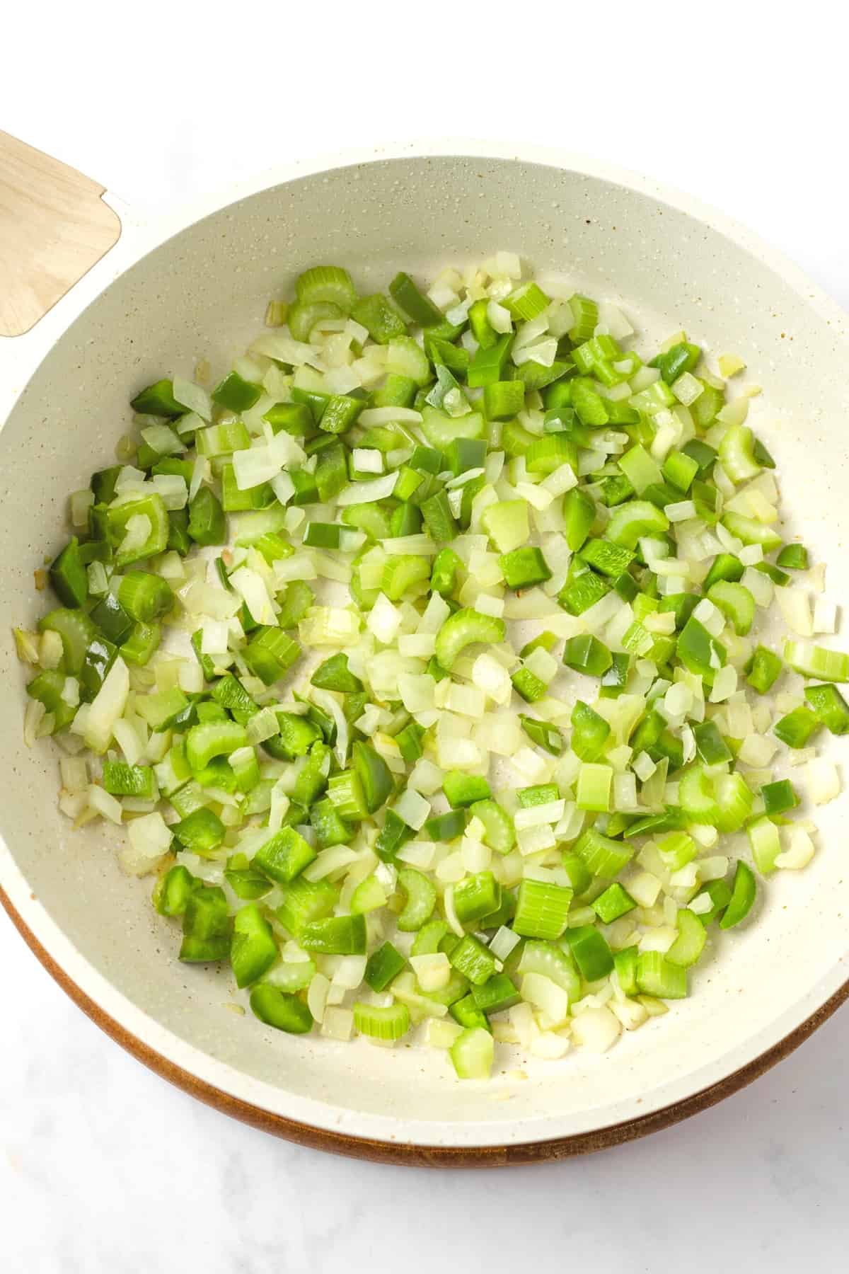 Celery and onions cooking in a skillet.