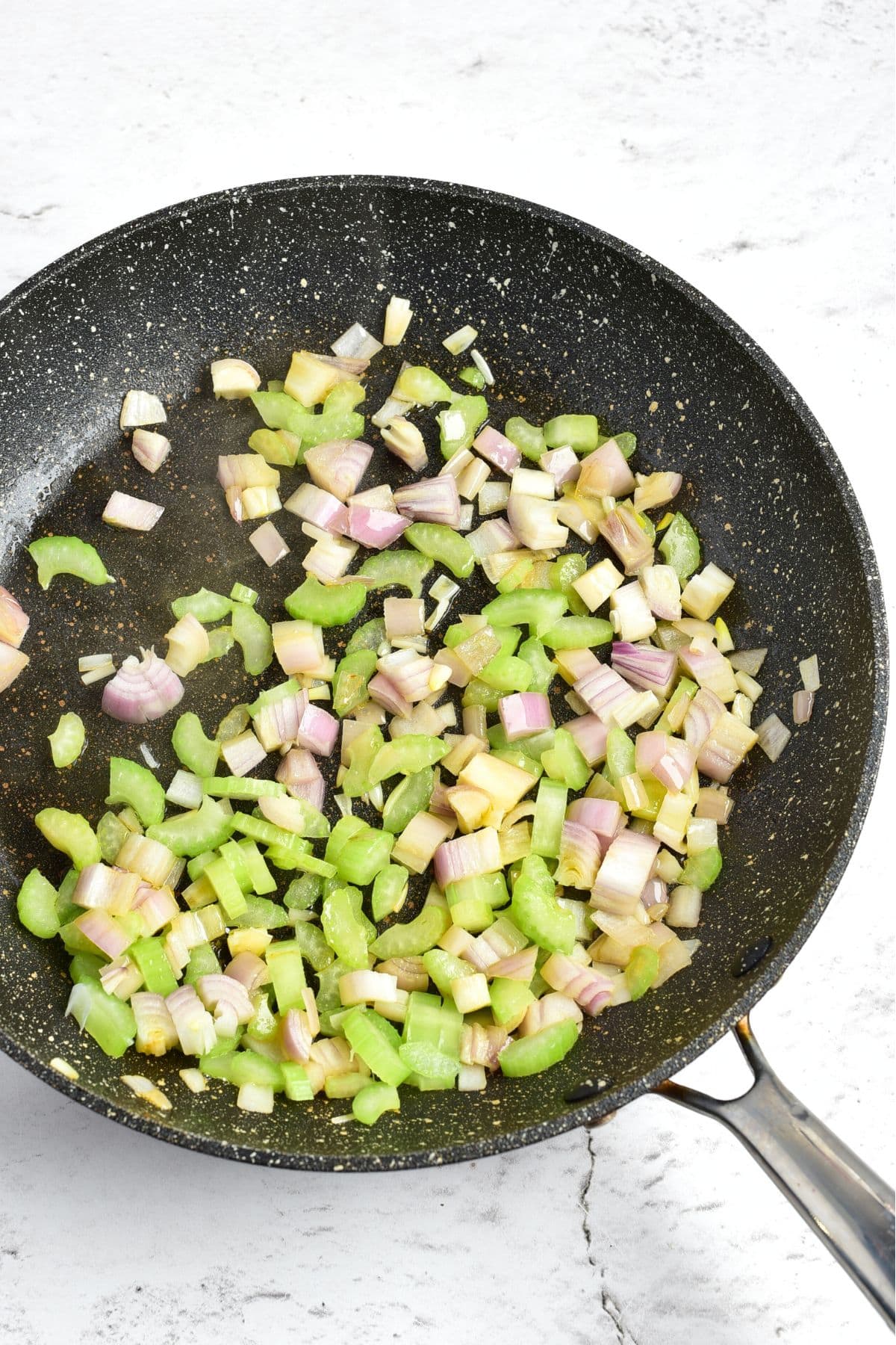 Sautéing diced celery and onions in skillet
