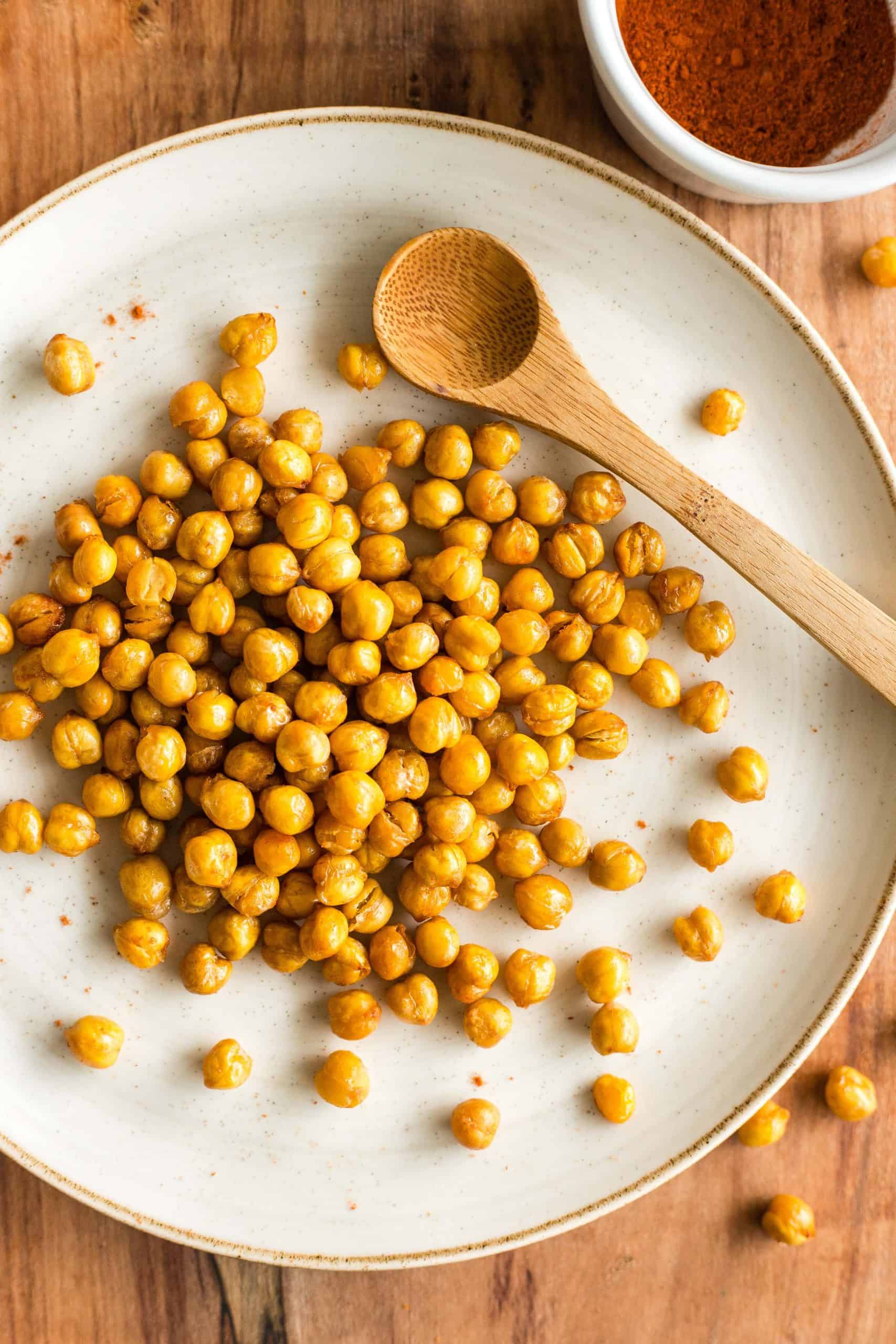 Crispy vegan air fryer chickpeas and a wooden spoon on a plate.