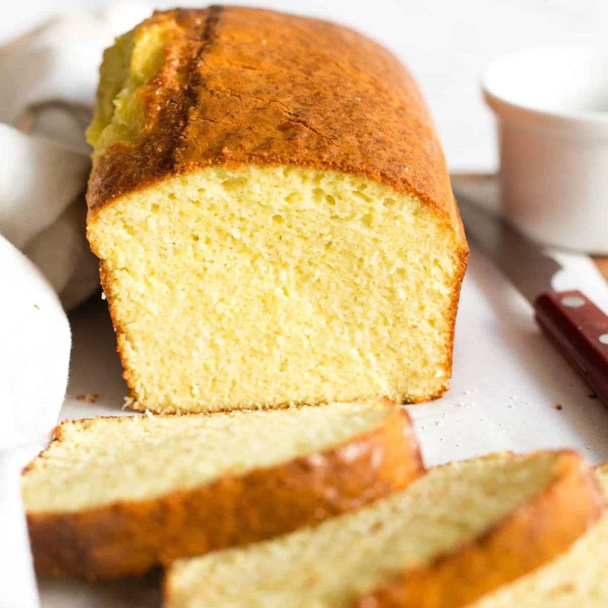 Half-sliced loaf of almond flour bread on parchment-lined board