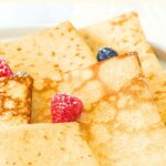 A plate of gluten-free almond flour crepes topped with berries