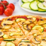 Pizza topped with sliced mushrooms and zucchini