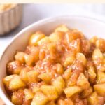 A bowl of apple pie filling on wooden board.