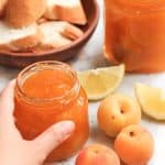 Hand reaching for jar of apricot jam