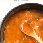 Wooden spoon stirring in pot of homemade apricot jam