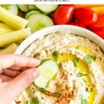 Dipping a sliced cucumber into a bowl of dip.