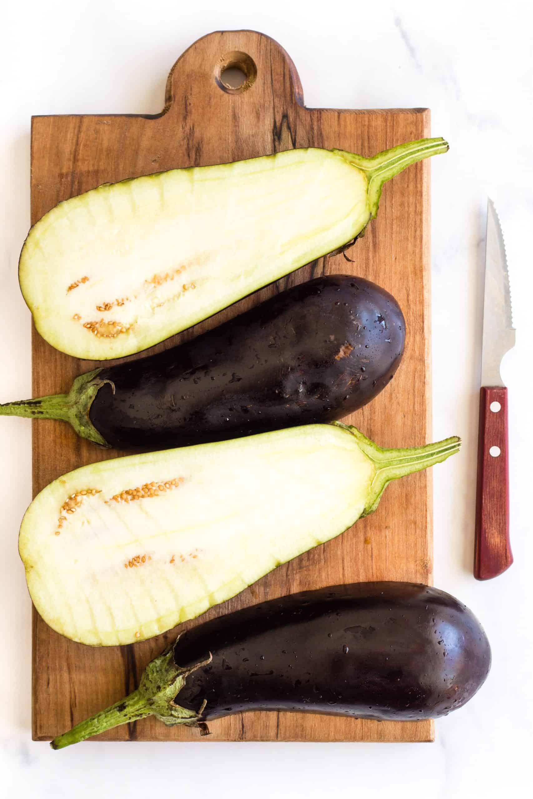Eggplant halves on a wooden board.