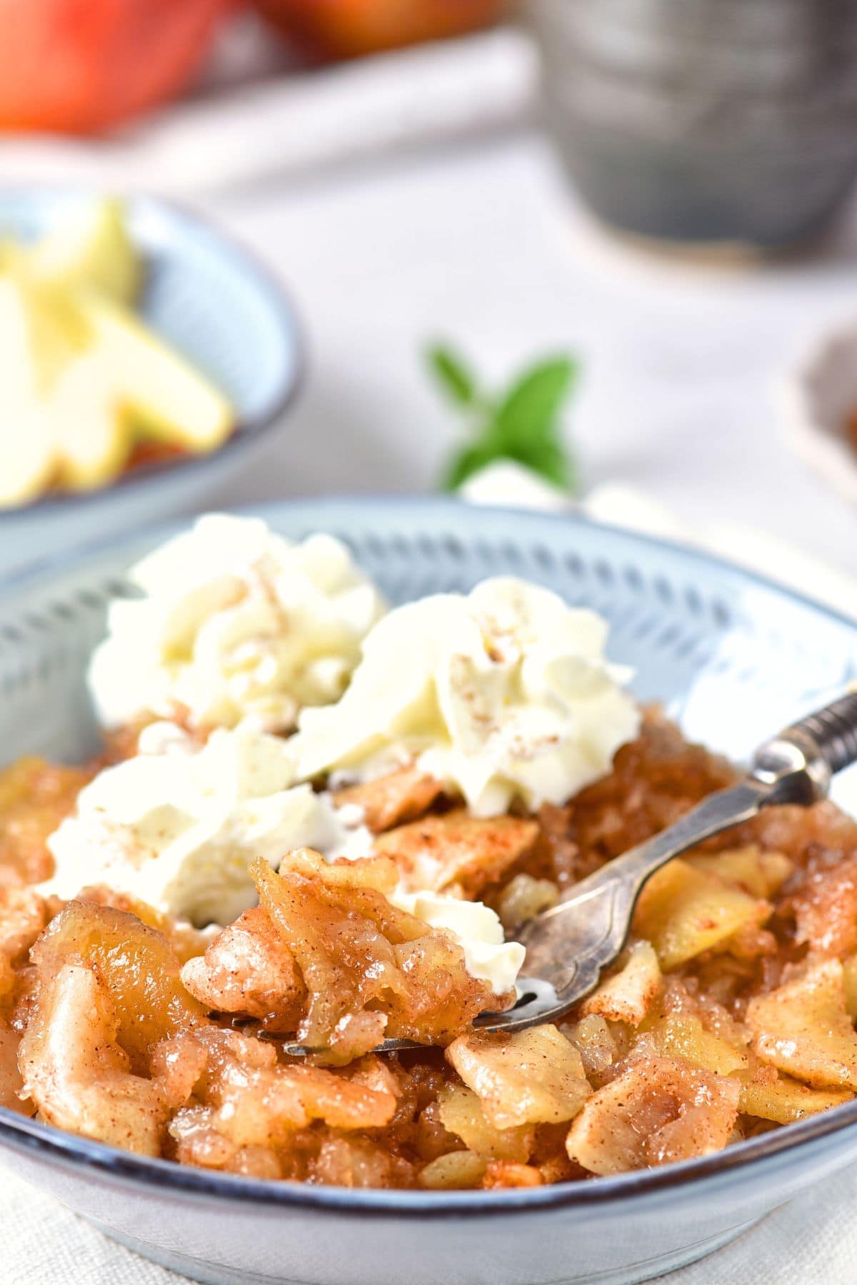 Holding up a forkful of baked apple slices and whipped cream