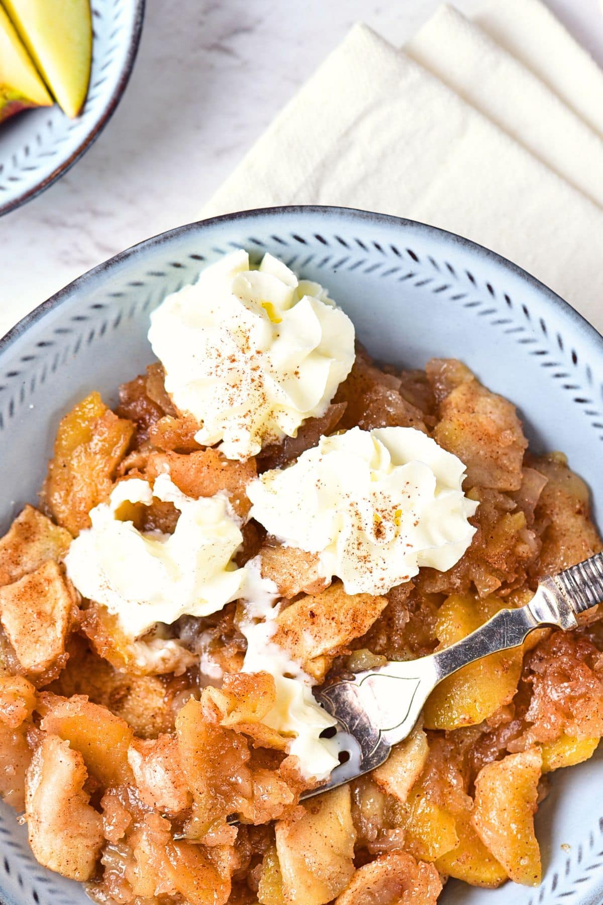 Top down view of a fork in a bowl of healthy baked apples.