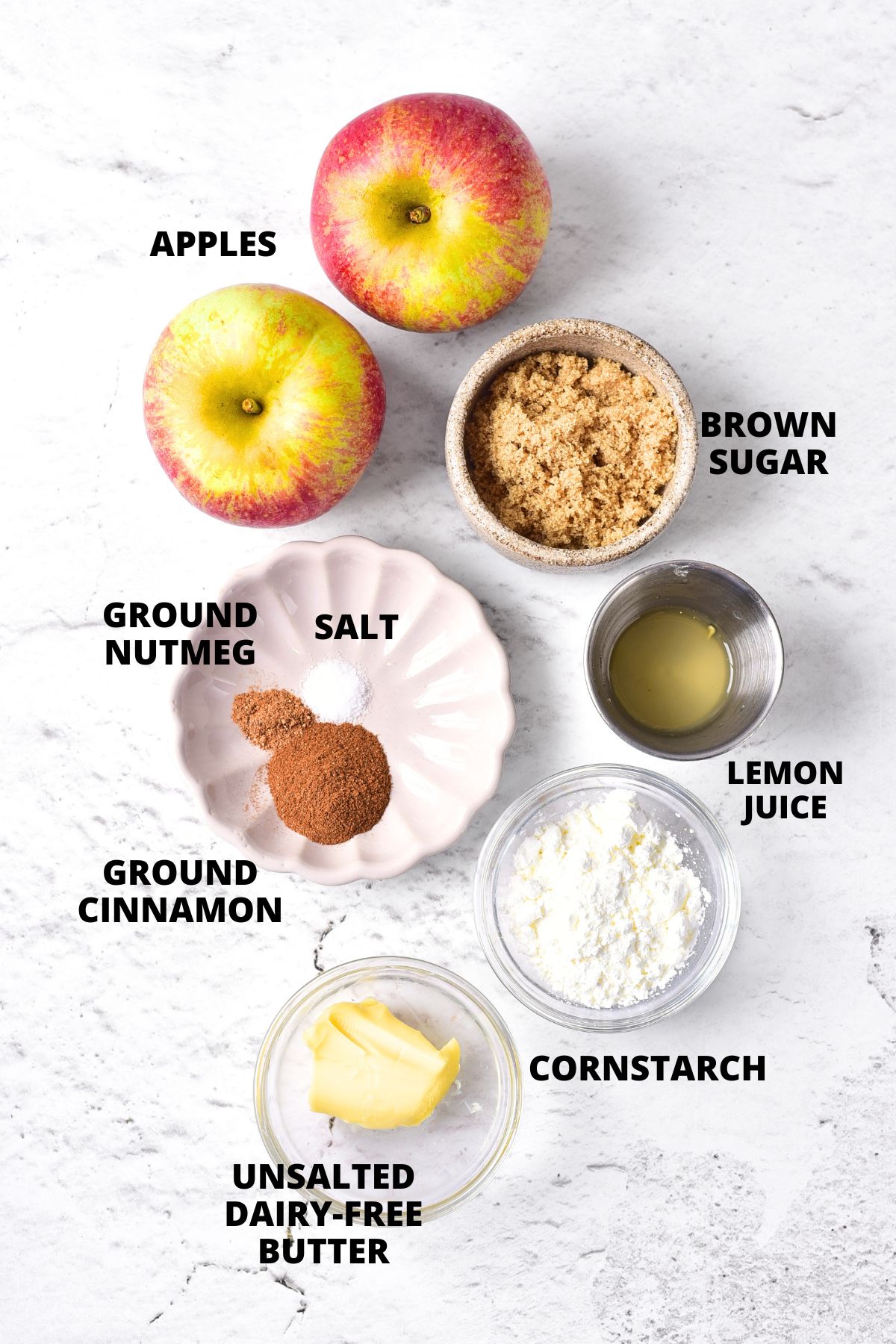 Ingredients for baked apples recipe laid out on marble board.