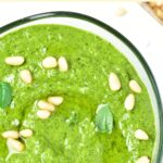 Top down view of a bowl of basil pesto topped with pine nuts