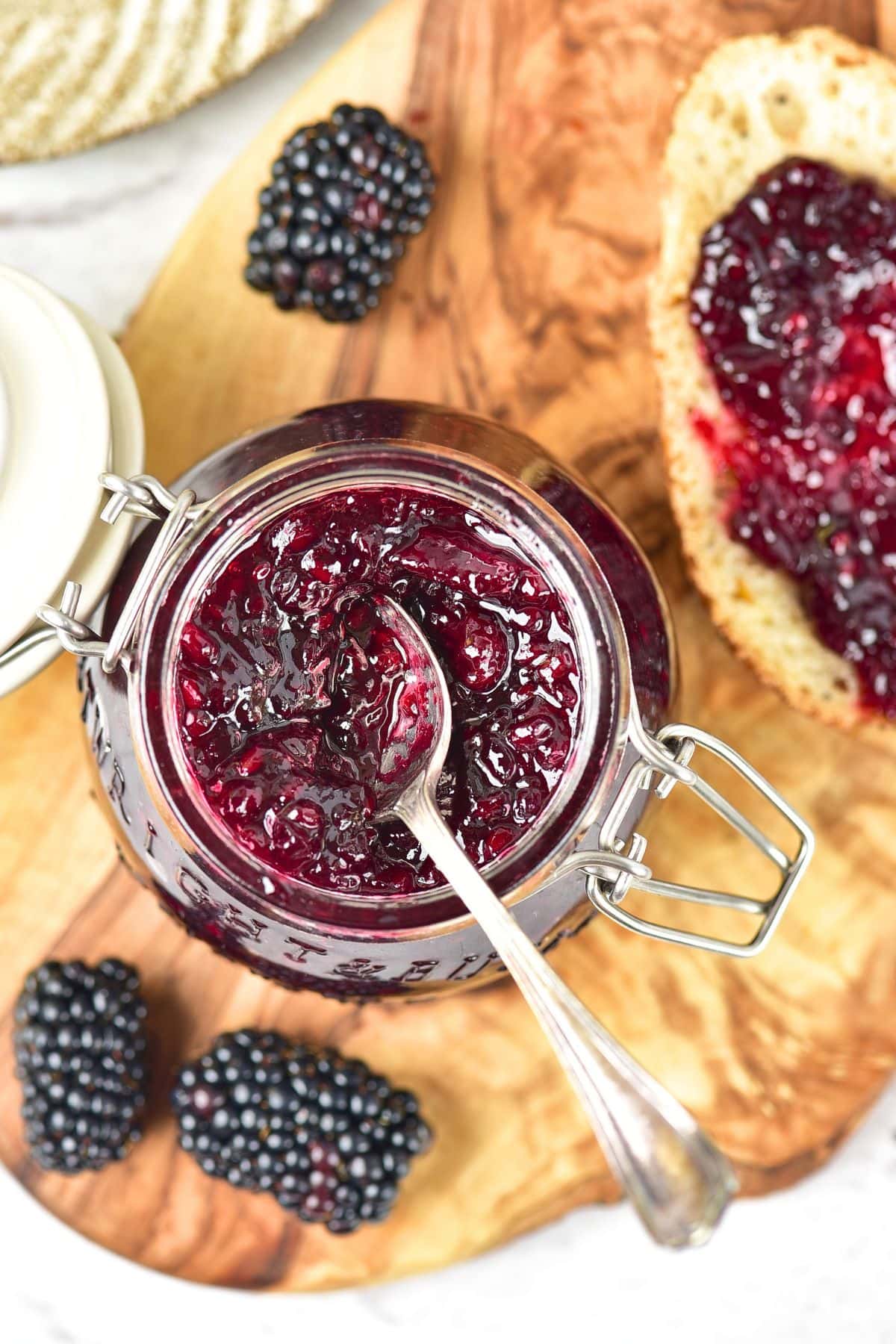 A jar of 3-ingredient blackberry jam on wooden board.