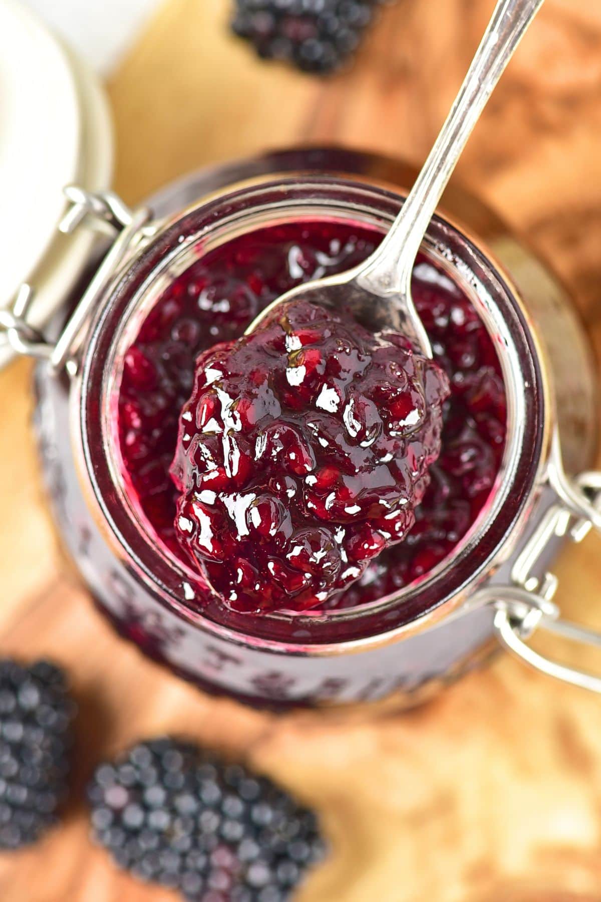 Holding a spoonful of homemade blackberry jam from a jar