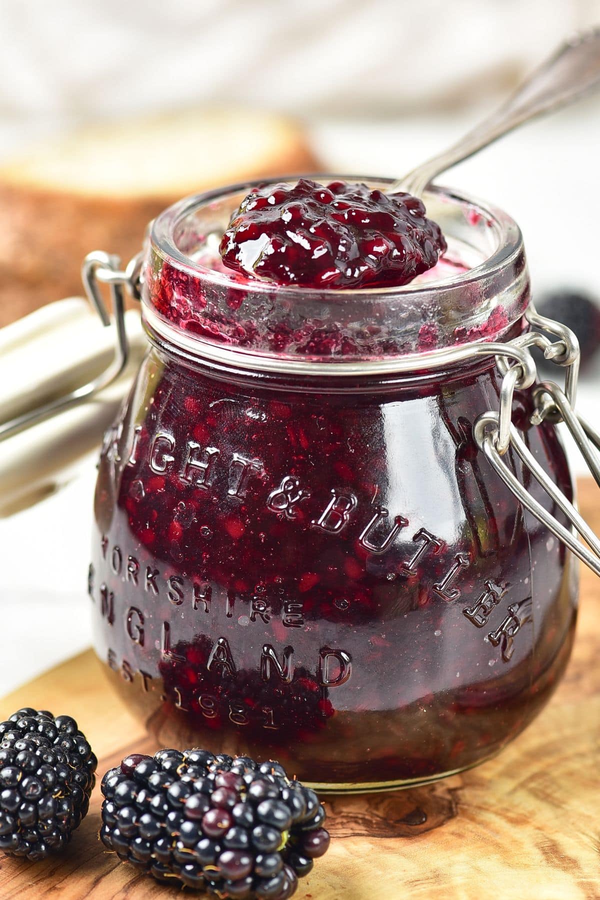 Taking a spoonful of blackberry jam from a jar.