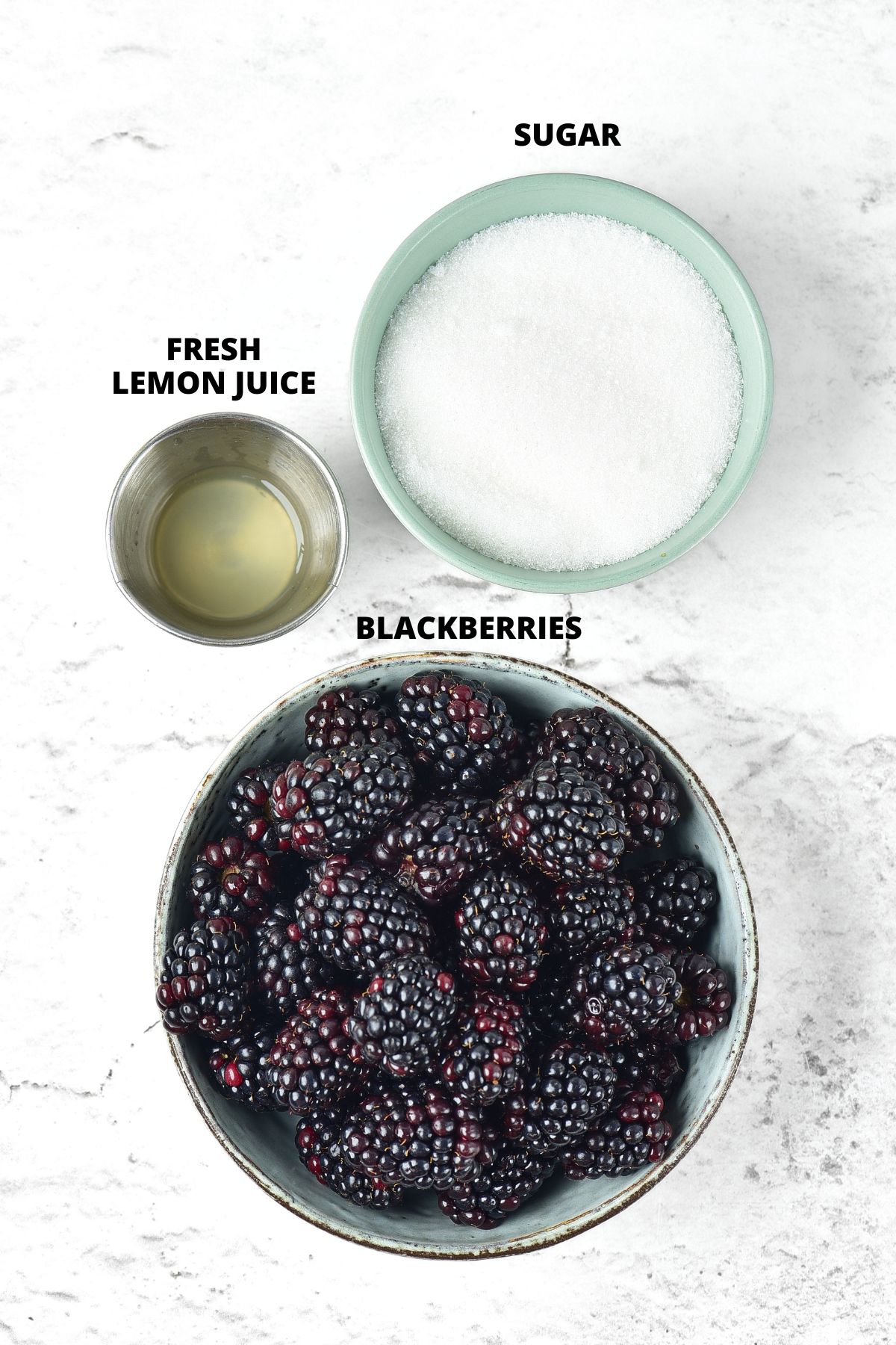 Ingredients for blackberry jam recipe laid out on marble board.