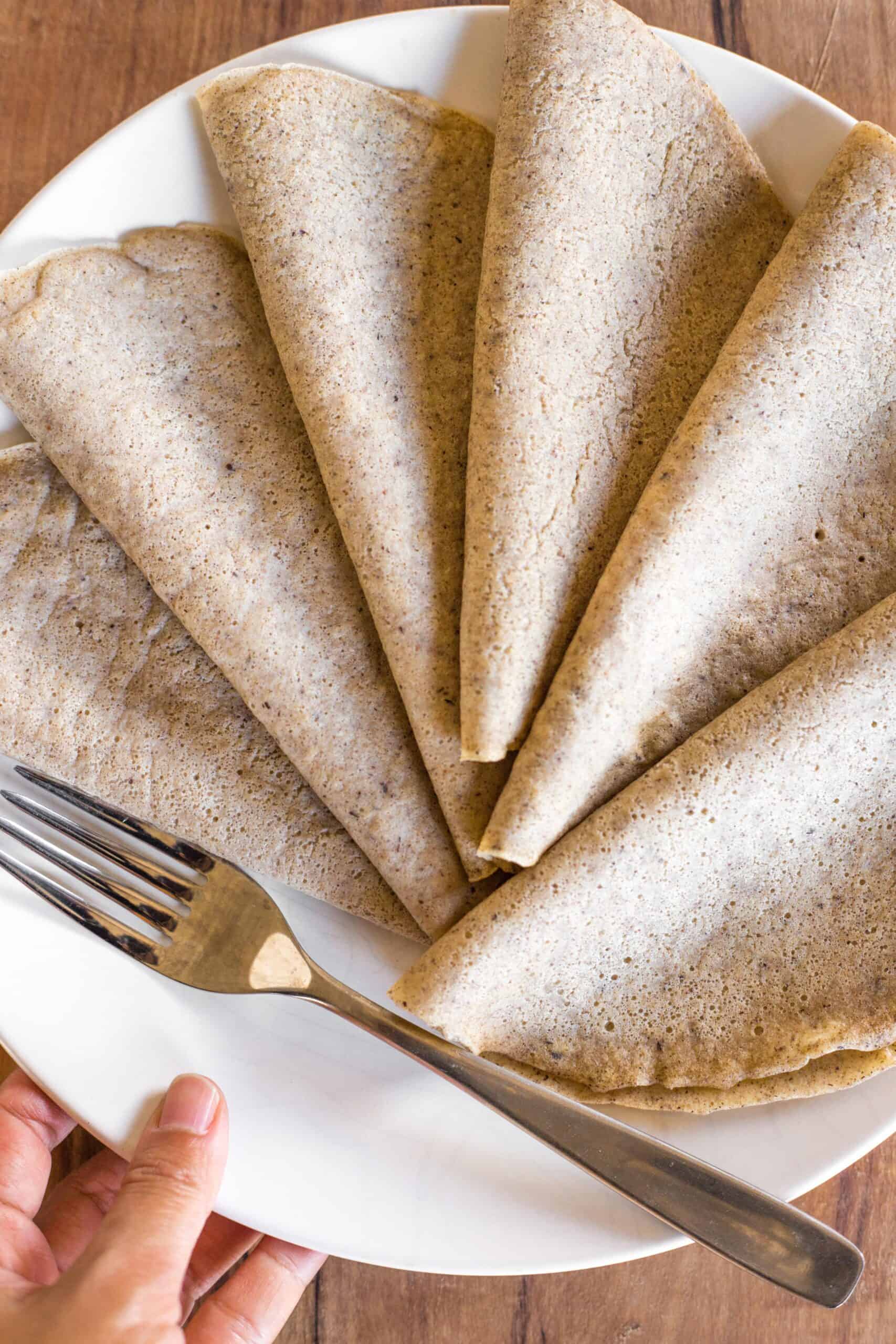 Folded gluten-free buckwheat crepes on a plate on a wooden board.