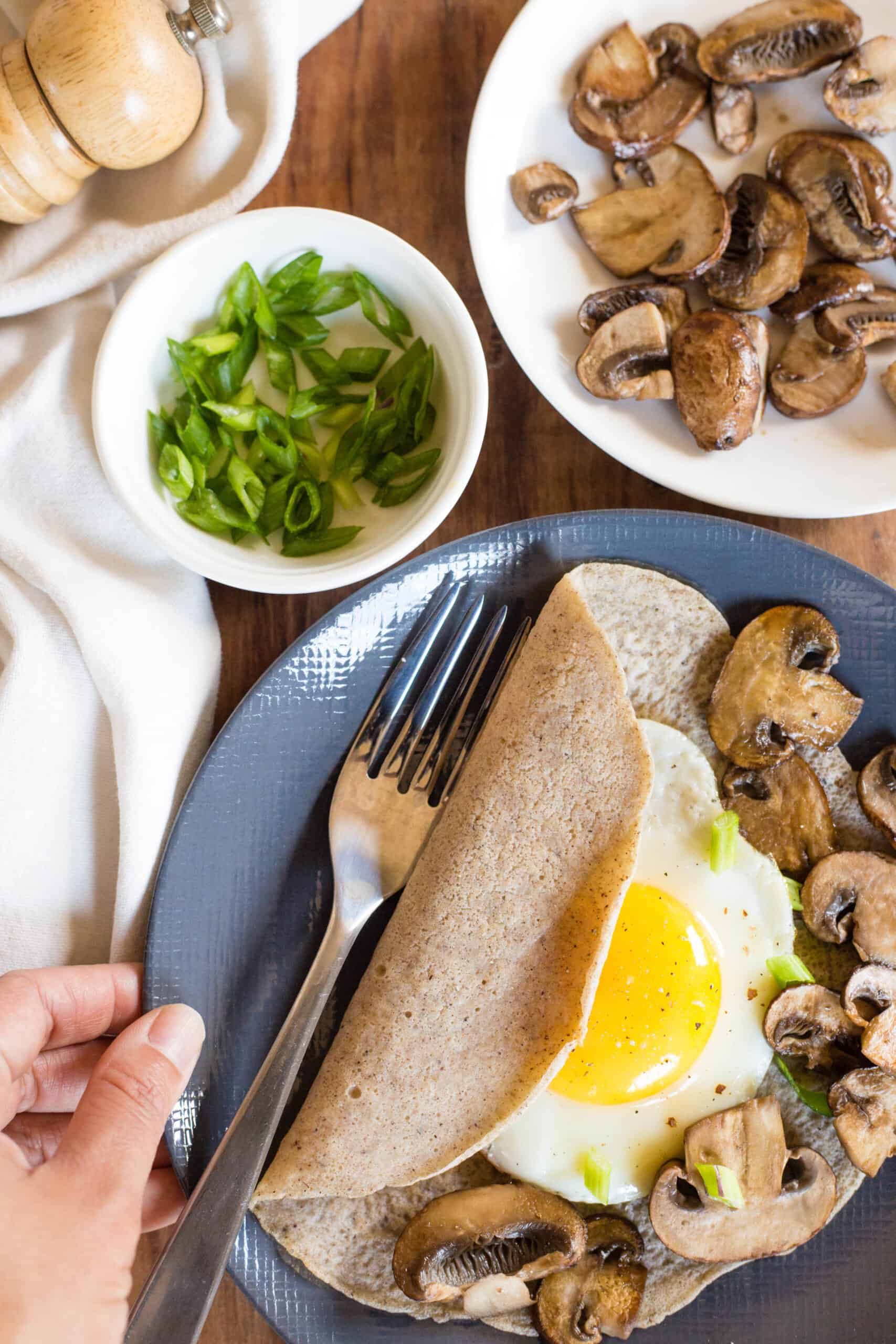 Holding a plate with a savory buckwheat crepe filled with an egg and mushrooms.