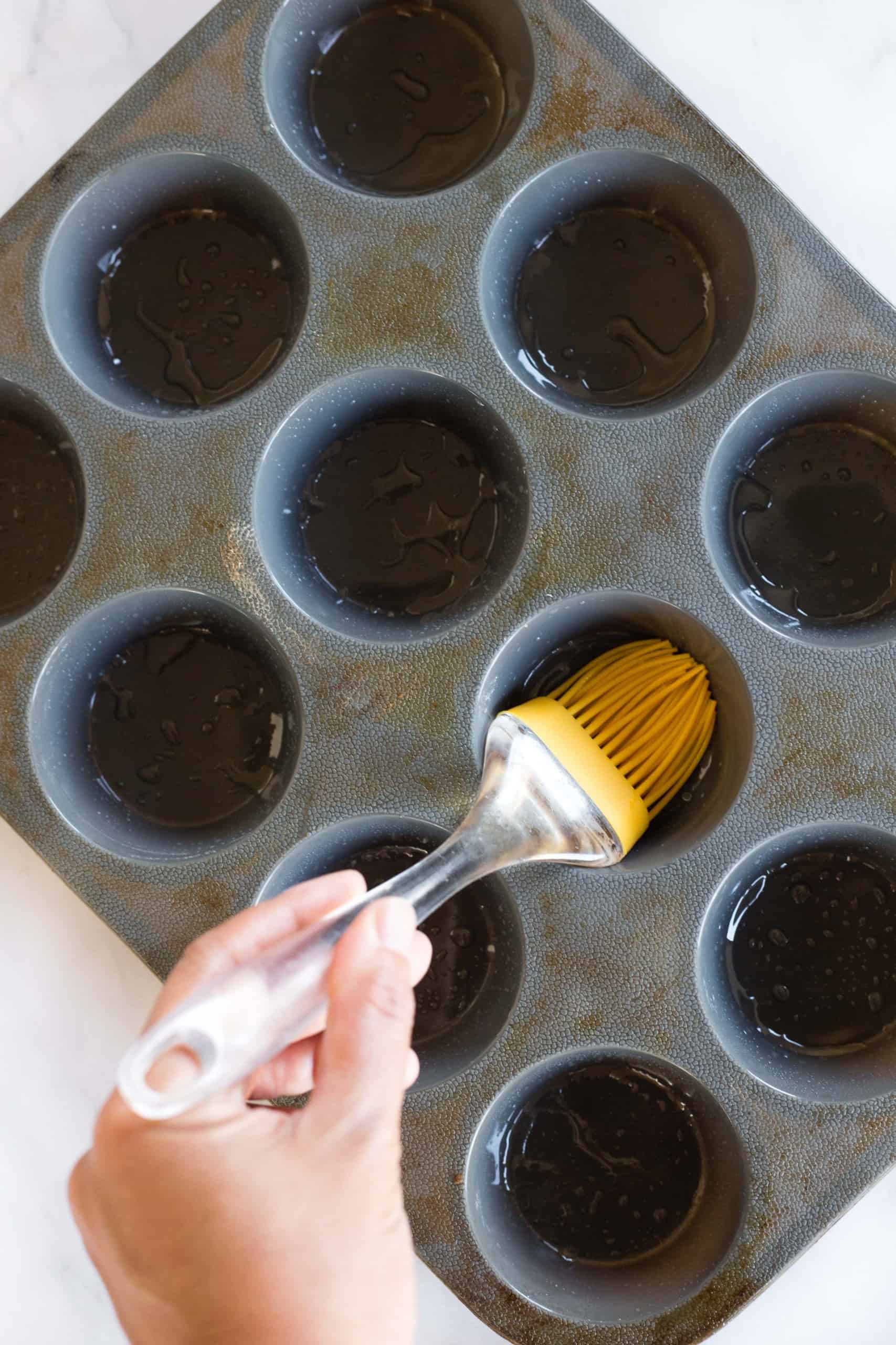 Using a silicon brush to grease muffin mold.