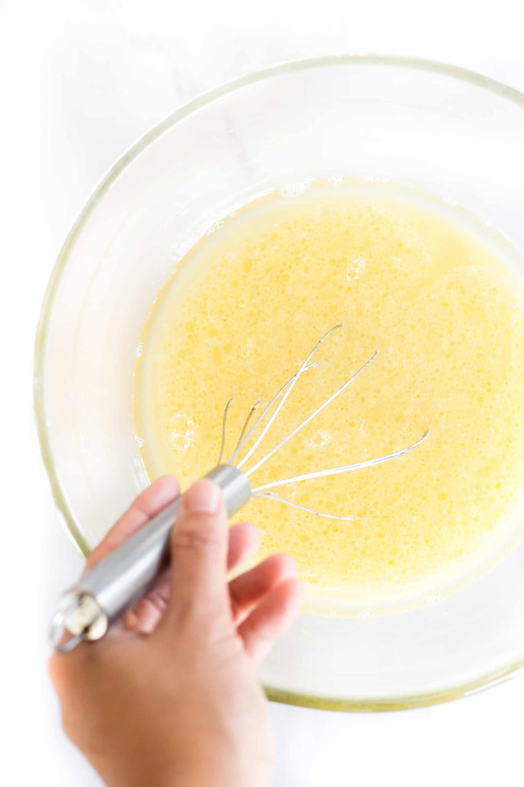 Whisking a yellow mixing in glass mixing bowl.