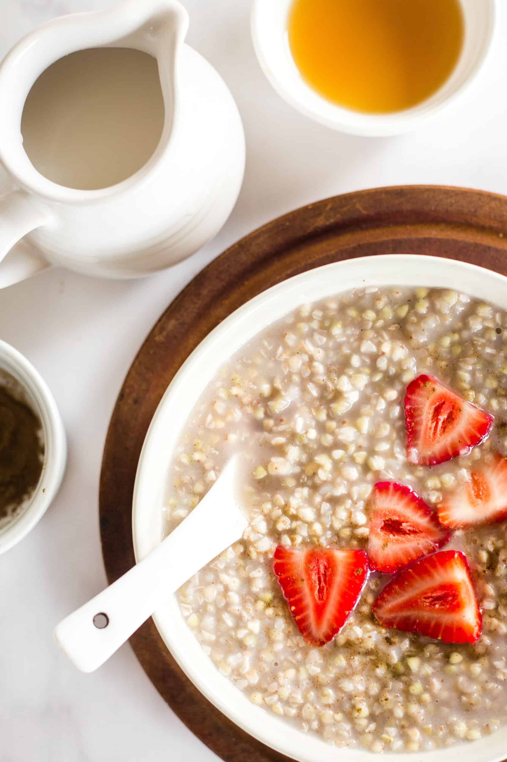 A bowl of strawberries and buckwheat porridge on a wooden board.