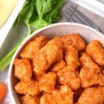 Top down view of bowl of buffalo chicken bites with vegetables.