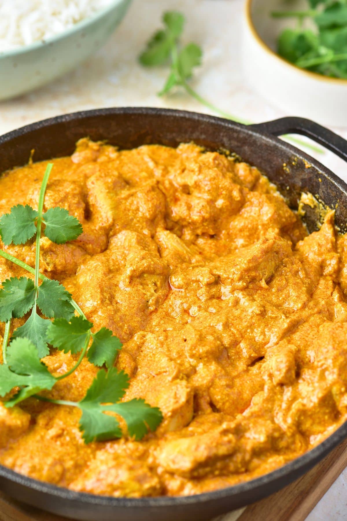 Up close view of gluten-free butter chicken and fresh parsley in skillet